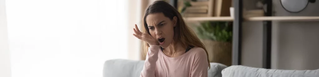 Woman checking her breath and reacting to bad breath, indicating a need for halitosis treatment or dental care.